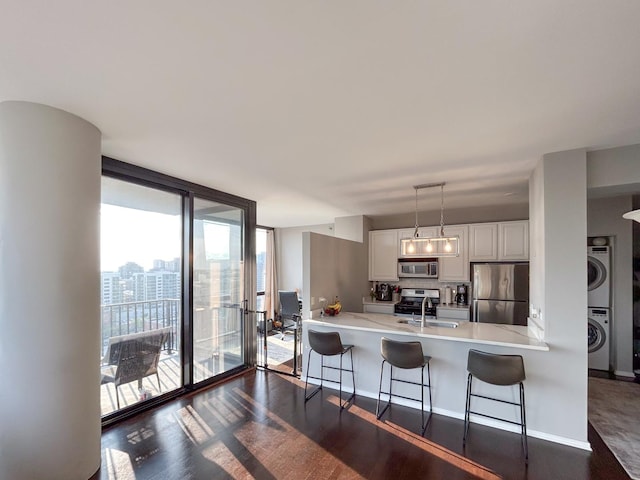 210 S Desplaines St Unit 1410, Chicago, IL 60661 - kitchen with stainless steel appliances, stacked washing machine and dryer, expansive windows, a peninsula, and white cabinetry