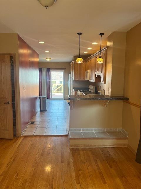 6111 S Menard Ave, Chicago, IL 60638 - kitchen with brown cabinetry, light wood-type flooring, white microwave, a peninsula, and baseboards
