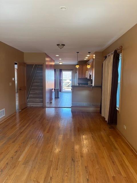 6111 S Menard Ave, Chicago, IL 60638 - unfurnished living room featuring stairs, light wood-style flooring, and baseboards