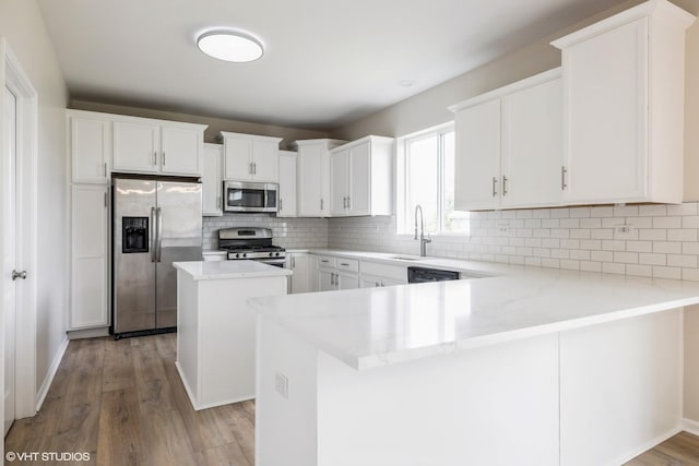 433 Minuet Cir, Volo, IL 60073 - kitchen with appliances with stainless steel finishes, a peninsula, light wood-type flooring, decorative backsplash, and a kitchen island