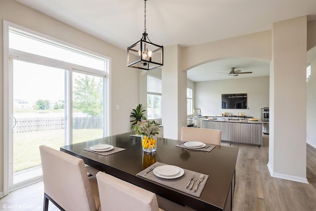 433 Minuet Cir, Volo, IL 60073 - dining area with arched walkways, light wood-type flooring, ceiling fan, and a chandelier