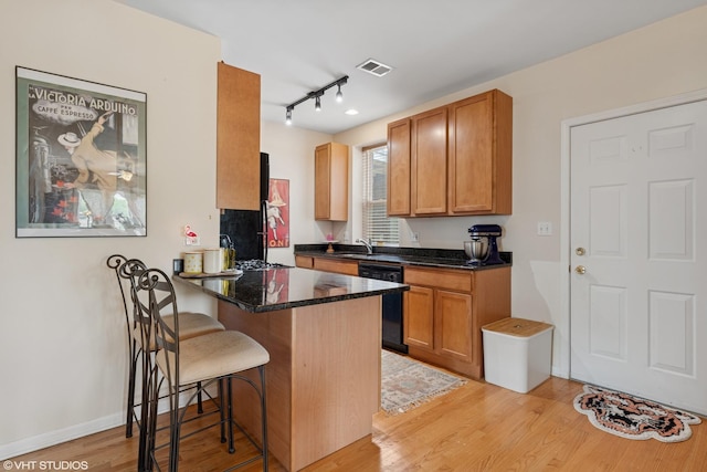 6100 N Rockwell St Unit 3S, Chicago, IL 60659 - kitchen with dishwasher, rail lighting, a breakfast bar area, light wood finished floors, and a peninsula