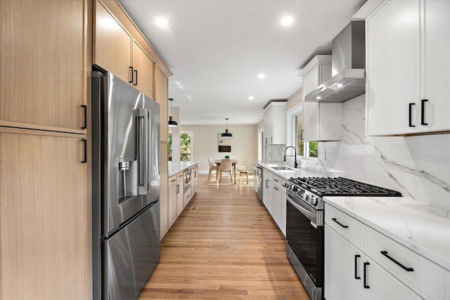 114 S Waverly Pl, Mount Prospect, IL 60056 - kitchen featuring appliances with stainless steel finishes, wall chimney exhaust hood, light wood-style flooring, backsplash, and light stone counters