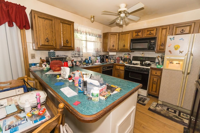 215 Chase Ct, Bolingbrook, IL 60440 - kitchen featuring black microwave, gas stove, white fridge with ice dispenser, brown cabinets, and a peninsula