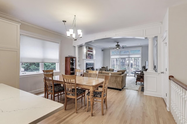 5021 N Kenmore Ave Unit 1S, Chicago, IL 60640 - dining room featuring a fireplace, light wood-style flooring, a ceiling fan, decorative columns, and plenty of natural light