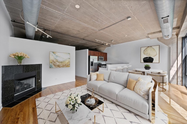 1150 W 15th St Unit 232, Chicago, IL 60608 - living area featuring rail lighting, light wood-style flooring, a tiled fireplace, and baseboards