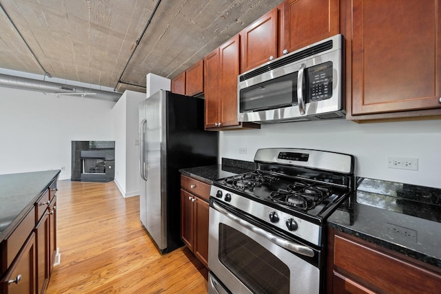 1150 W 15th St Unit 232, Chicago, IL 60608 - kitchen with stainless steel appliances, light wood-style floors, dark stone counters, and a tiled fireplace