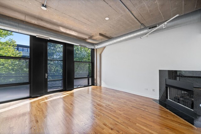 1150 W 15th St Unit 232, Chicago, IL 60608 - unfurnished living room featuring wood finished floors, a tiled fireplace, and baseboards