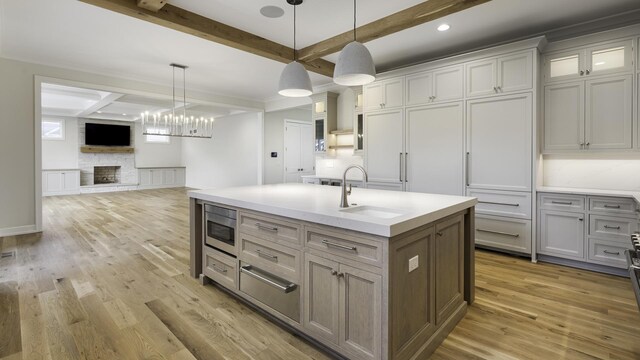 845 Tulip Ln, Naperville, IL 60540 - kitchen featuring a sink, stainless steel microwave, light wood-style flooring, beamed ceiling, and light countertops