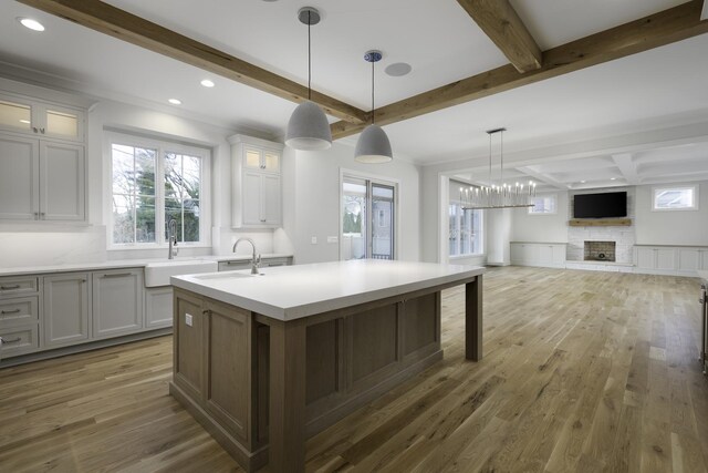 845 Tulip Ln, Naperville, IL 60540 - kitchen with beamed ceiling, a center island with sink, a sink, wood finished floors, and light countertops
