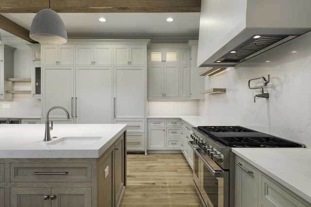 845 Tulip Ln, Naperville, IL 60540 - kitchen with wall chimney exhaust hood, high end range, a sink, light wood finished floors, and glass insert cabinets