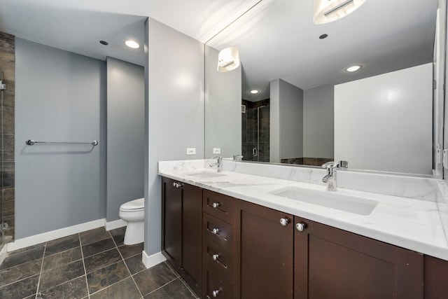 bathroom with double vanity, toilet, baseboards, a tile shower, and recessed lighting