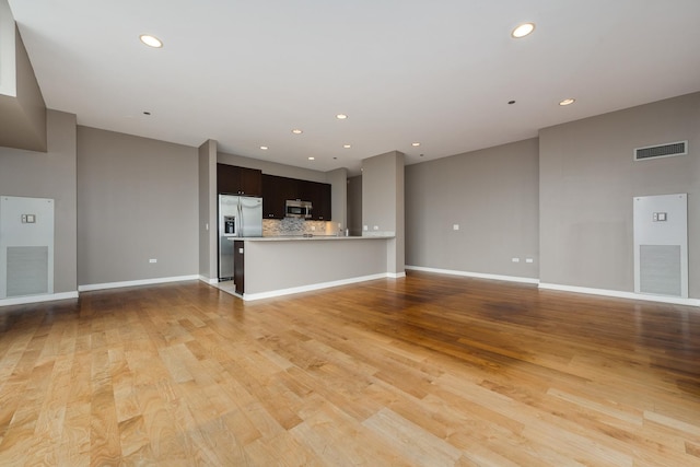 unfurnished living room with recessed lighting, light wood finished floors, and baseboards