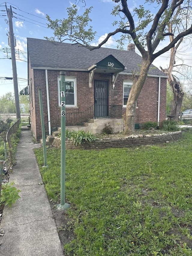 128 W 115th St, Chicago, IL 60628 - view of front facade featuring brick siding, a shingled roof, a front yard, and a chimney
