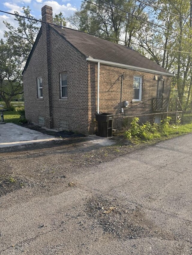 128 W 115th St, Chicago, IL 60628 - view of side of property with a chimney, brick siding, and a shingled roof