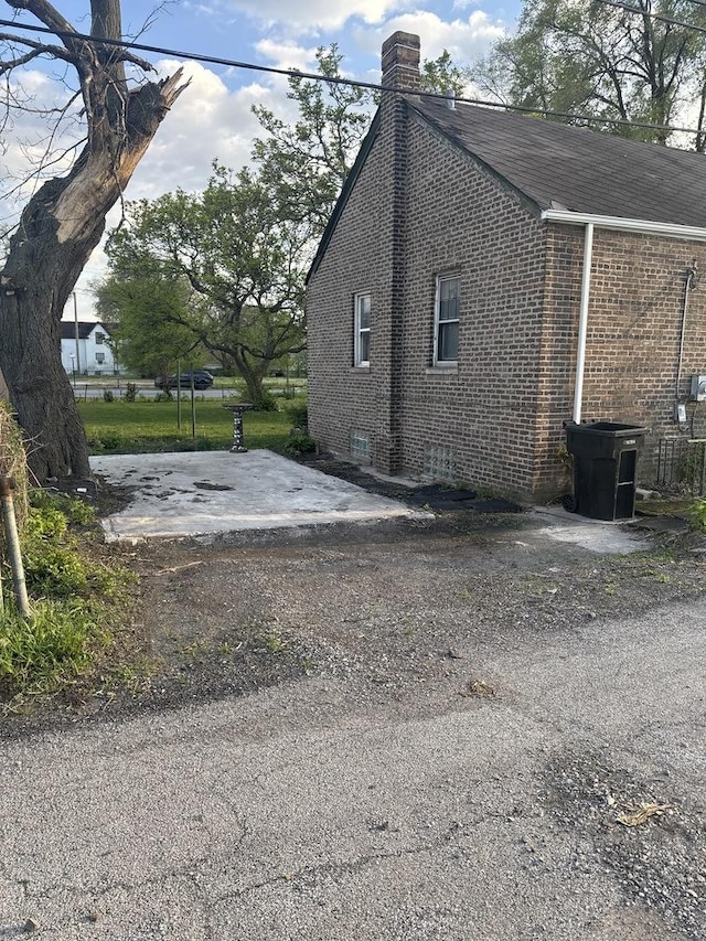 128 W 115th St, Chicago, IL 60628 - view of home's exterior featuring brick siding, a chimney, and roof with shingles