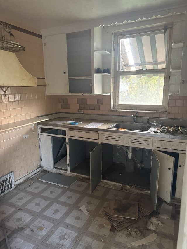 128 W 115th St, Chicago, IL 60628 - kitchen featuring a sink, decorative backsplash, light countertops, white cabinetry, and light flooring