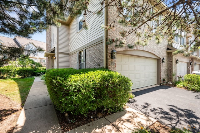 2119 Ivy Ridge Dr Unit 2119, Hoffman Estates, IL 60192 - view of side of home featuring driveway, brick siding, stone siding, and an attached garage