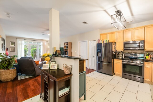 620 Mchenry Rd Unit 102, Wheeling, IL 60090 - kitchen featuring stainless steel appliances, dark countertops, light brown cabinetry, open floor plan, and decorative backsplash