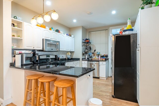 4848 W Belle Plaine Ave Unit 2R, Chicago, IL 60641 - kitchen with stainless steel dishwasher, black gas range oven, a peninsula, a breakfast bar area, and open shelves