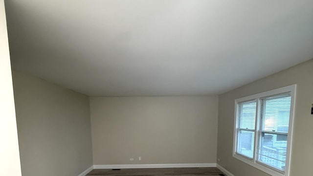 spare room featuring dark wood finished floors and baseboards