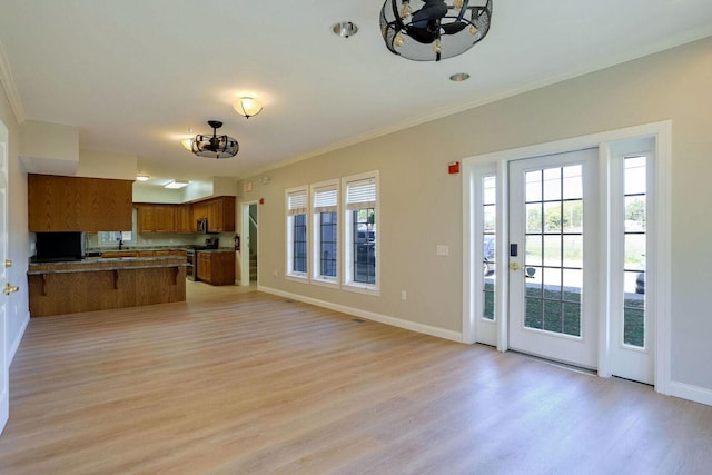 504 E Church St, Champaign, IL 61820 - kitchen featuring brown cabinetry, stainless steel gas range oven, a peninsula, light wood-type flooring, and open floor plan