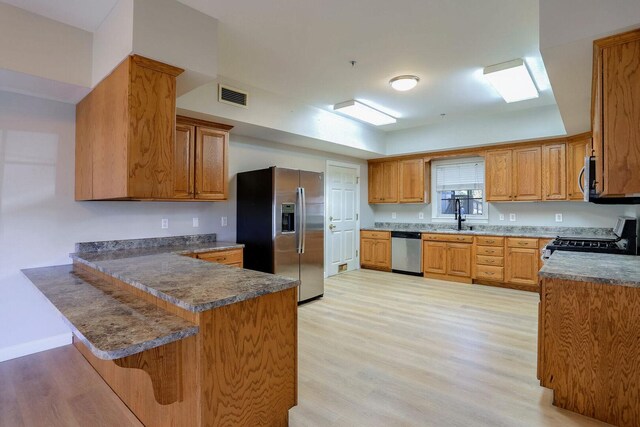 504 E Church St, Champaign, IL 61820 - kitchen with stainless steel appliances, a peninsula, light wood-style floors, and a breakfast bar area