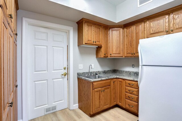 504 E Church St, Champaign, IL 61820 - kitchen with freestanding refrigerator, a sink, light wood-type flooring, brown cabinets, and baseboards