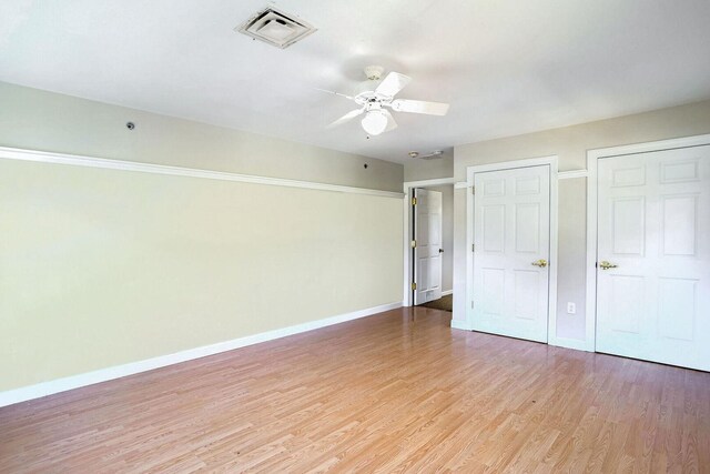 504 E Church St, Champaign, IL 61820 - unfurnished bedroom featuring baseboards, light wood-style floors, and a ceiling fan