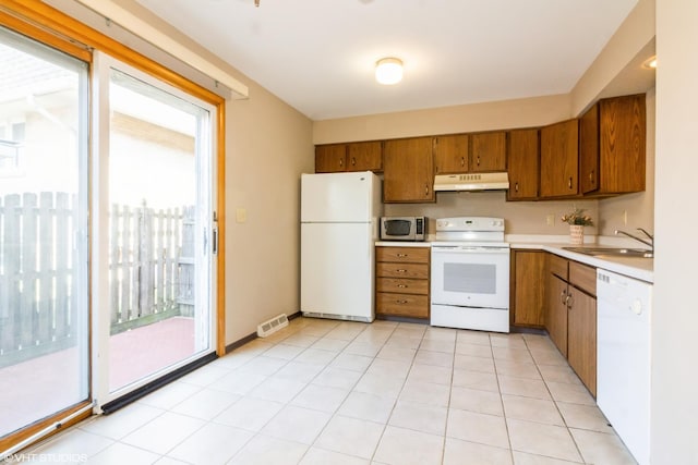 613 E 3rd St Unit 4, Lockport, IL 60441 - kitchen with white appliances, under cabinet range hood, brown cabinetry, light countertops, and light tile patterned flooring