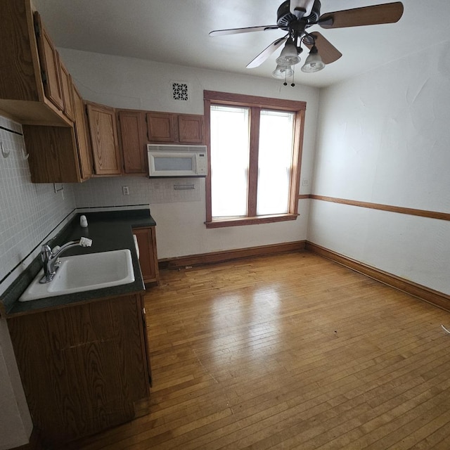 3054 N Kedzie Ave Unit 1F, Chicago, IL 60618 - kitchen with white microwave, a sink, hardwood / wood-style floors, dark countertops, and a ceiling fan