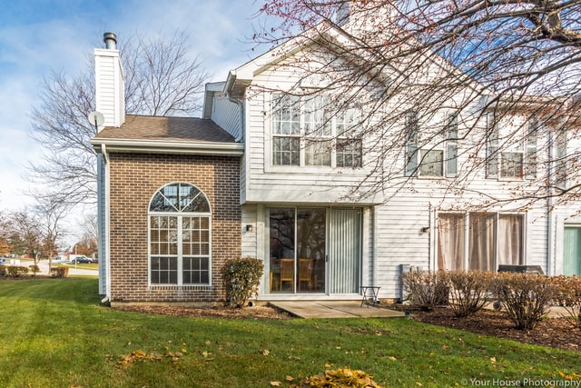 1611 Woodcrest Cir, Mundelein, IL 60060 - rear view of house featuring a lawn, brick siding, a chimney, and a patio area