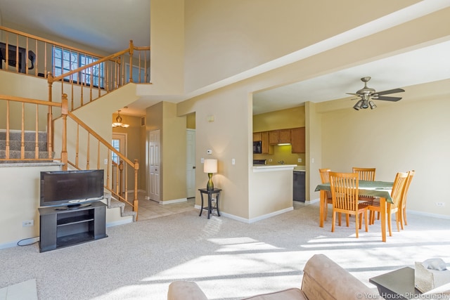 1611 Woodcrest Cir, Mundelein, IL 60060 - living area with stairway, light carpet, ceiling fan, a chandelier, and a high ceiling