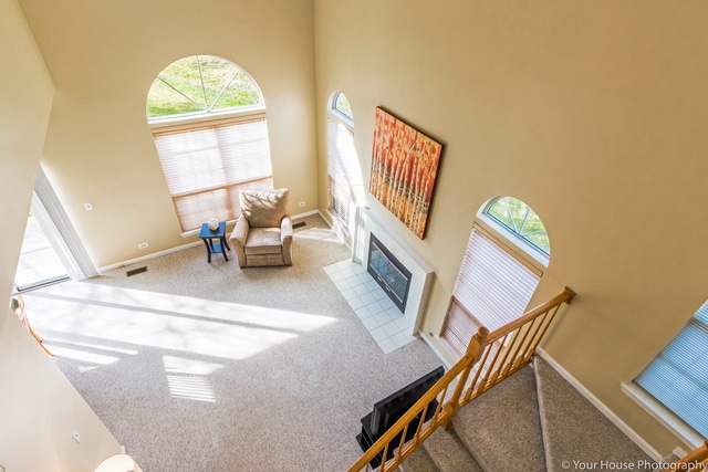 1611 Woodcrest Cir, Mundelein, IL 60060 - unfurnished living room featuring carpet, a towering ceiling, a tile fireplace, and stairs