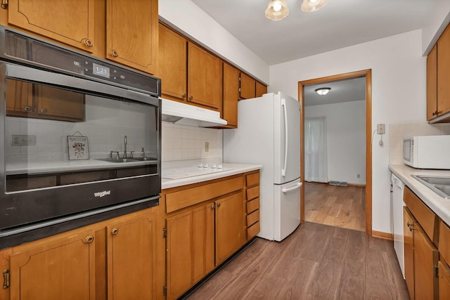 1635 N 4012th Rd, Earlville, IL 60518 - kitchen featuring white appliances, under cabinet range hood, light wood-type flooring, decorative backsplash, and brown cabinetry