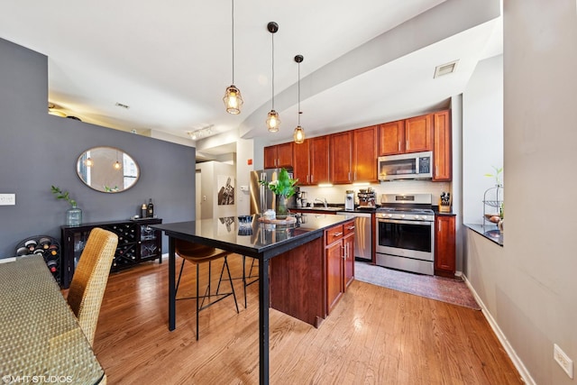 208 W Washington St Unit 1205, Chicago, IL 60606 - kitchen with appliances with stainless steel finishes, dark countertops, light wood finished floors, and a kitchen breakfast bar