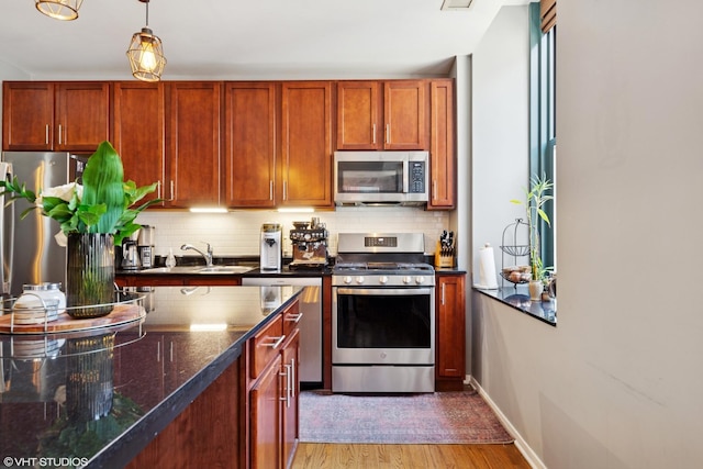 208 W Washington St Unit 1205, Chicago, IL 60606 - kitchen featuring appliances with stainless steel finishes, backsplash, light wood-type flooring, and pendant lighting