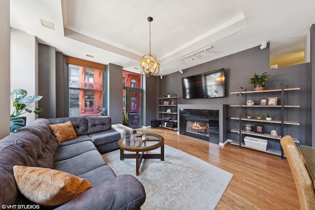 208 W Washington St Unit 1205, Chicago, IL 60606 - living room with wood finished floors, a chandelier, a glass covered fireplace, and a tray ceiling