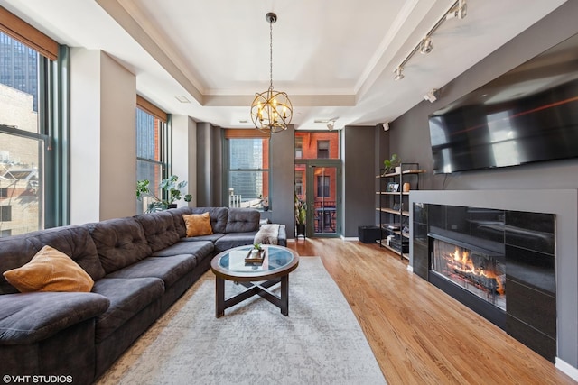 208 W Washington St Unit 1205, Chicago, IL 60606 - living area featuring wood finished floors, a tray ceiling, rail lighting, a chandelier, and a glass covered fireplace