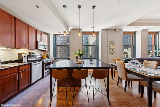 208 W Washington St Unit 1205, Chicago, IL 60606 - kitchen with appliances with stainless steel finishes, plenty of natural light, wood finished floors, and dark countertops