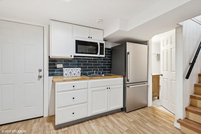 5247 N California Ave, Chicago, IL 60625 - kitchen with white microwave, freestanding refrigerator, butcher block countertops, white cabinetry, and backsplash