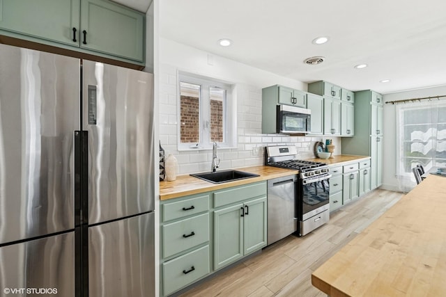 5247 N California Ave, Chicago, IL 60625 - kitchen featuring stainless steel appliances, butcher block counters, green cabinetry, light wood-type flooring, and recessed lighting