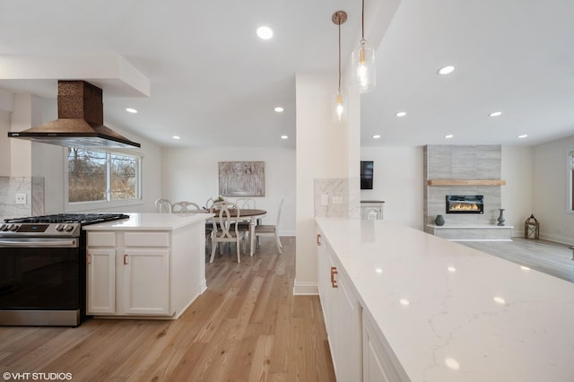 316 Nellie Ct, Glenview, IL 60025 - kitchen with stainless steel gas range, ventilation hood, light wood-style floors, white cabinetry, and a tile fireplace