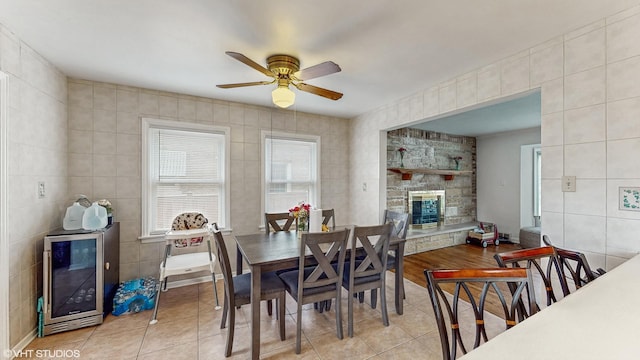 1910 N 76th Ct, Elmwood Park, IL 60707 - dining room with wine cooler, tile walls, light tile patterned floors, ceiling fan, and a stone fireplace