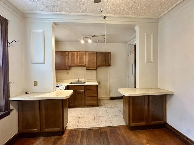 1453 W Elmdale Ave Unit 1, Chicago, IL 60660 - kitchen with a peninsula, light countertops, a sink, light wood-style flooring, and a textured ceiling