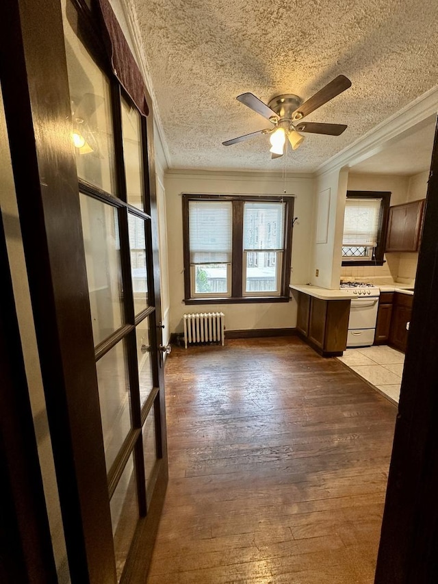 1453 W Elmdale Ave Unit 1, Chicago, IL 60660 - kitchen featuring radiator heating unit, white range with gas stovetop, crown molding, light countertops, and a textured ceiling