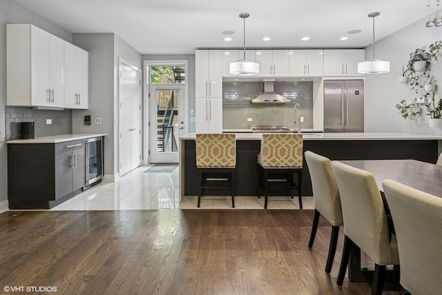 1350 W Diversey Pkwy Unit 1, Chicago, IL 60614 - kitchen featuring built in fridge, wall chimney exhaust hood, wine cooler, decorative backsplash, and modern cabinets