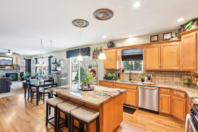 949 Ruthenbeck Ln, New Lenox, IL 60451 - kitchen featuring appliances with stainless steel finishes, a center island, light wood-type flooring, a fireplace, and tasteful backsplash