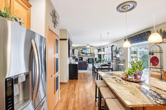 949 Ruthenbeck Ln, New Lenox, IL 60451 - kitchen featuring stainless steel fridge with ice dispenser, light wood-style floors, light stone countertops, a kitchen bar, and hanging light fixtures