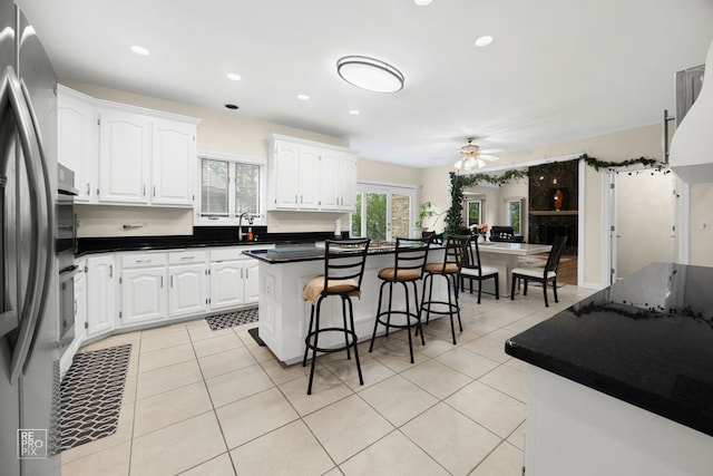 401 Jason Ln, Schaumburg, IL 60173 - kitchen featuring a breakfast bar area, white cabinets, freestanding refrigerator, ceiling fan, and dark countertops